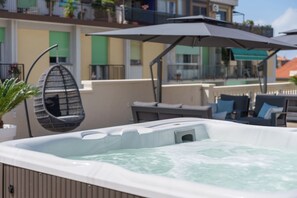 Un jacuzzi con dosel, una hamaca colgante y mobiliario de exterior.