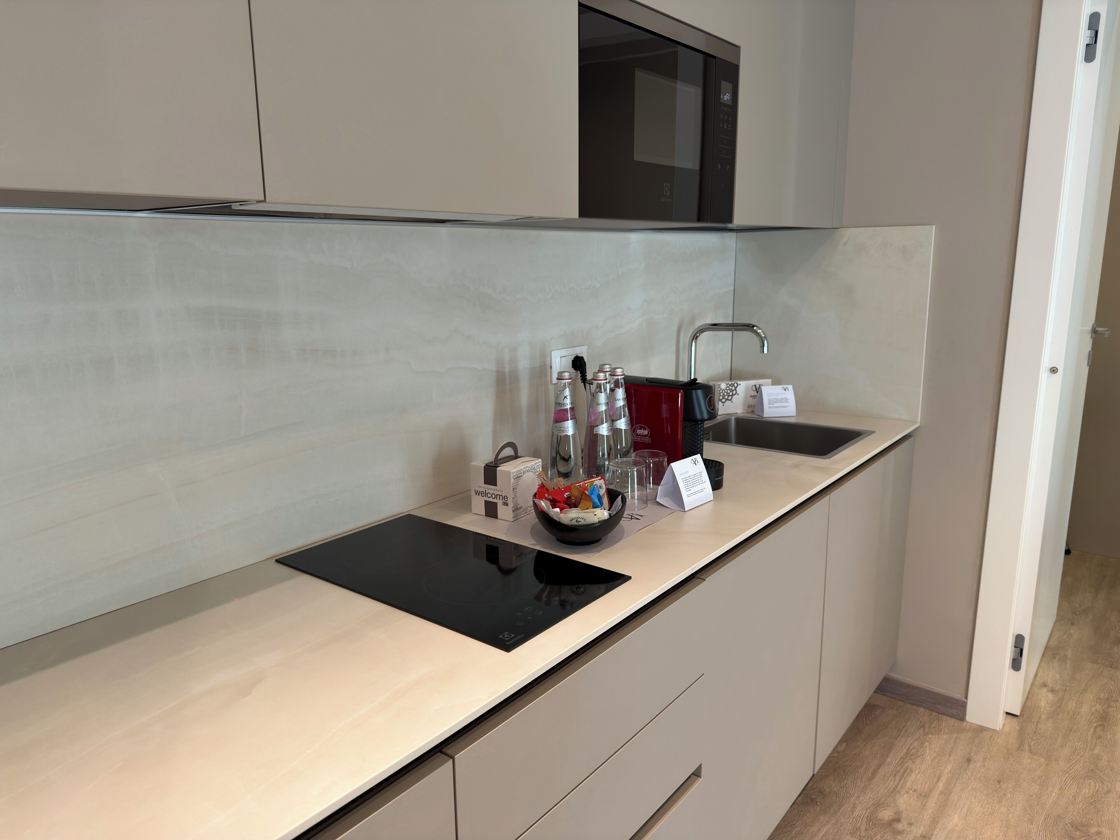 Una cocina moderna con microondas integrado, un fregadero y una placa de inducción negra.