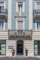 Un edificio de estilo arquitectónico clásico, con una entrada destacada que incluye un arco decorativo y un balcón con barandillas de metal ornamentado.