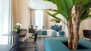 A modern hotel lobby with a seating area, a reception desk, and a large plant. - VI SUITES (Viareggio)