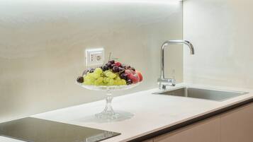 Una cocina con microondas integrado, un lavamanos y un frutero sobre la encimera.