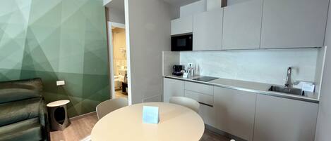 A modern kitchen with a microwave, sink, and coffee maker. There is a dining area with a round table and chairs.