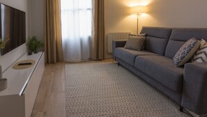 A modern living room with a grey sofa, a standing lamp, a TV on a white console, and a window with curtains. - Beautiful renovated apartment in central Logroño with WIFI (Logroño)