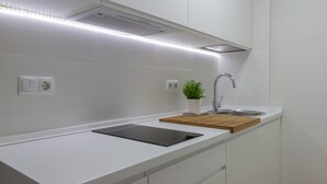 A modern kitchen with white cabinetry, a black induction cooktop, a wooden countertop, a stainless steel sink, and a small potted plant. - Beautiful renovated apartment in central Logroño with WIFI (Logroño)