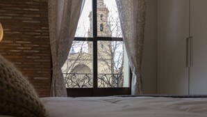 A bedroom with a large window, a brick wall, a bed, and a wardrobe. - Beautiful renovated apartment in central Logroño with WIFI (Logroño)