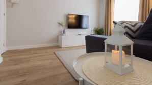 A modern living room with a flat-screen TV, a grey sofa, a white side table, and a white lantern on a round table. - Beautiful renovated apartment in central Logroño with WIFI (Logroño)