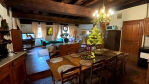 A cozy dining area with a wooden table and chairs, a Christmas tree, and a television in the background. - FAMILY HOME IN THE HEART OF TOWN (Saint-Gervais-d'Auvergne)