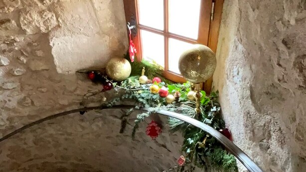 A spiral staircase in a rustic stone building with a small window and festive decorations. - FAMILY HOME IN THE HEART OF TOWN (Saint-Gervais-d'Auvergne)