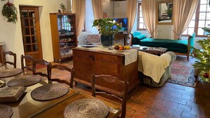 A cozy living room with a wooden dining table, chairs, a sofa, and a television. - FAMILY HOME IN THE HEART OF TOWN (Saint-Gervais-d'Auvergne)