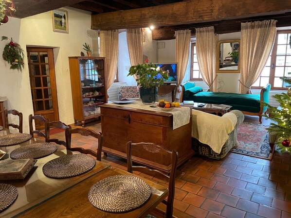 Un salón acogedor con una mesa de madera, sillas, un sofá y un televisor.