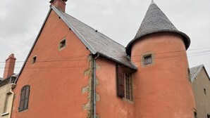 A historic building with a red facade, a turret, and a traditional window design. - FAMILY HOME IN THE HEART OF TOWN (Saint-Gervais-d'Auvergne)