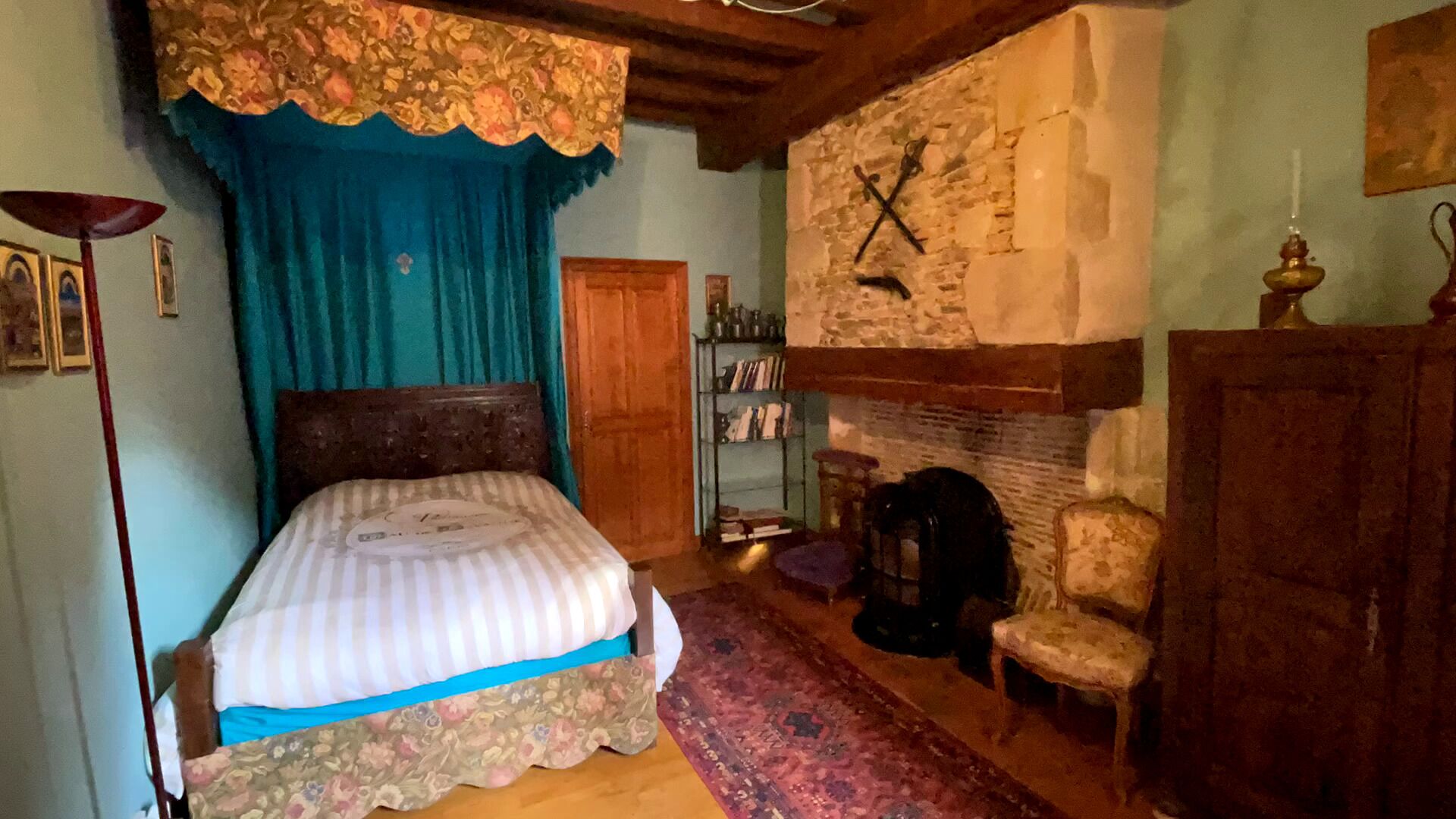 Quarto com cama, estante, poltrona e lareira.
