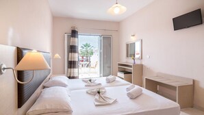 A hotel room with two beds, a TV, a desk, and a balcony with a view. - Yakinthos Hotel (Zakynthos)