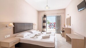 A modern hotel room with a large bed, a bedside table, a TV mounted on the wall, and a balcony with a view of the city. - Yakinthos Hotel (Zakynthos)