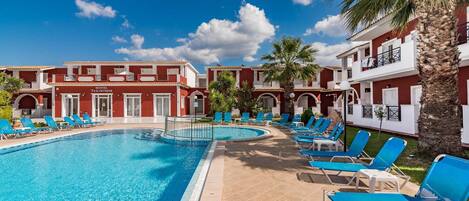 Un hotel con piscina, sillas de descanso azules y palmeras.