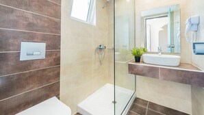 A modern bathroom with a glass shower enclosure, a white sink, and a small potted plant. - Yakinthos Hotel (Zakynthos)