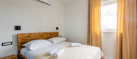 A neatly made bed with a wooden headboard, white linens, and rolled towels.