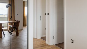 Un intérieur moderne avec un plancher en bois, un coin repas comprenant une table et des chaises, et un grand miroir qui agrandit visuellement l’espace.