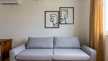 A modern living room with a grey sofa, two abstract wall art pieces, and a wooden side table.