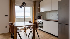Une cuisine moderne dotée d’un réfrigérateur en acier inoxydable, de meubles en bois et d’un coin repas avec une table en bois et des chaises en cuir.