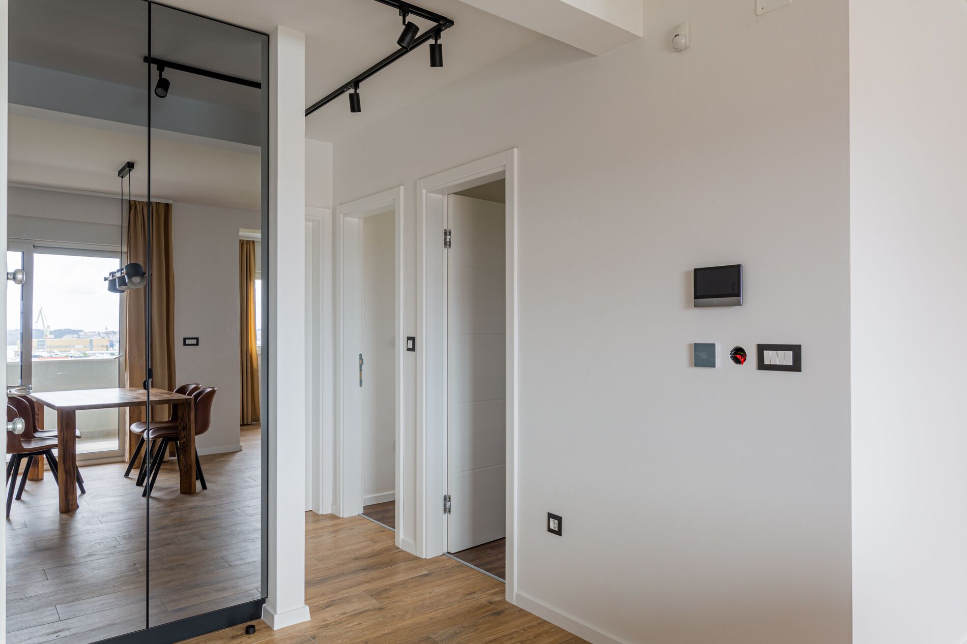 Ein modernes Interieur mit Essbereich, einem Flur und Blick durch eine Glastür.