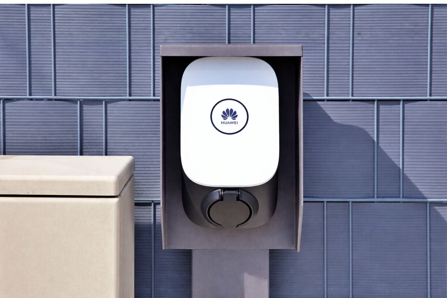 A Huawei charging station mounted on a wall with a tiled background.
