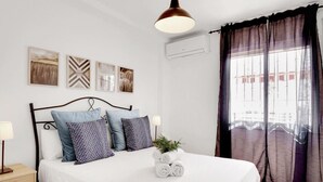 A neatly made bed with patterned pillows, a bedside lamp, and a small plant on the nightstand. - Quiet apartment between golf and sea with pool (Rincón de la Victoria)