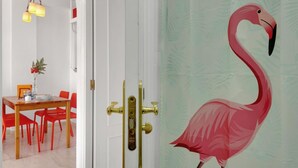 A room with a white door, red chairs, a wooden table, and a decorative flamingo on the wall. - Quiet apartment between golf and sea with pool (Rincón de la Victoria)
