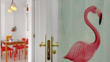 A room with a white door, red chairs, a wooden table, and a decorative flamingo on the wall.