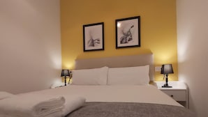 A neatly made bed with a grey blanket and white pillows, two bedside lamps, and two framed artworks on the wall. - Large central apartment in Malaga for 4, ideal for family or couple (Málaga)