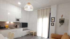 A modern living room with a sofa, a dining table with chairs, a kitchen area with a microwave, and a TV. - Large central apartment in Malaga for 4, ideal for family or couple (Málaga)