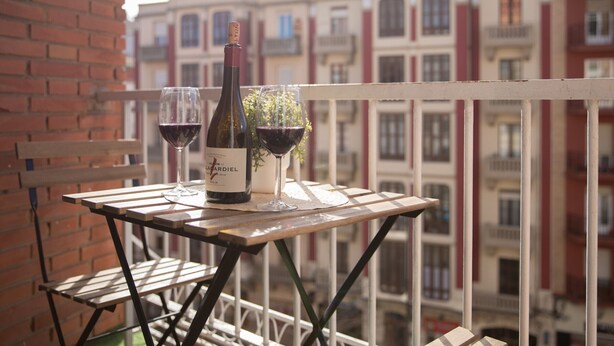 A balcony with a table set for two, featuring a bottle of wine and two glasses. - Central Apartment in Logroño: 5-Min Walk to Calle Laurel & Gran Vía, Next to City Hall (Logroño)