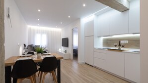 A modern kitchen with white cabinets, a wooden countertop, and a built-in oven. There is a dining area with a wooden table and black chairs. - Central Apartment in Logroño: 5-Min Walk to Calle Laurel & Gran Vía, Next to City Hall (Logroño)