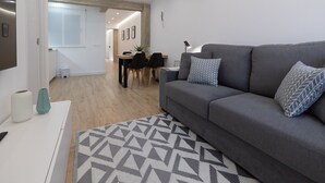 A modern living room with a grey sofa, patterned rug, and a dining area with a table and chairs. - Central Apartment in Logroño: 5-Min Walk to Calle Laurel & Gran Vía, Next to City Hall (Logroño)