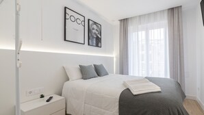 A modern bedroom with a bed, bedside tables, a nightstand, a wall-mounted TV, and framed artwork. - Central Apartment in Logroño: 5-Min Walk to Calle Laurel & Gran Vía, Next to City Hall (Logroño)