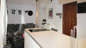 Een moderne woonkamer met een bank, een eettafel en een keuken voorzien van een koelkast en een magnetron.