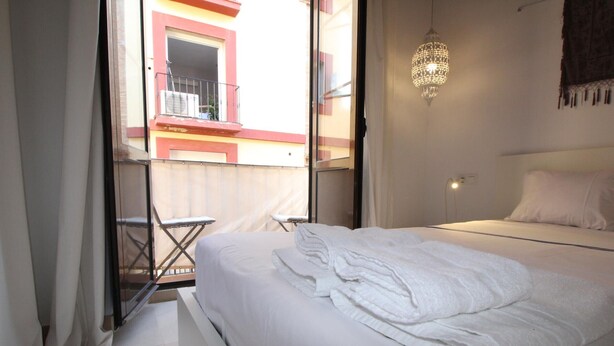 Een hotelkamer met een bed, een klein balkon en een hanglamp.