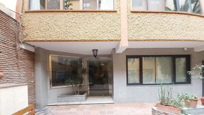 En innergård med en bänk, krukväxter och en byggnadsingång.