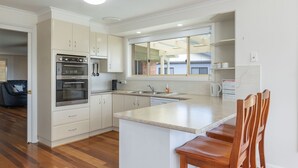 Una cocina moderna con armarios blancos, electrodomésticos de acero inoxidable y un amplio ventanal.