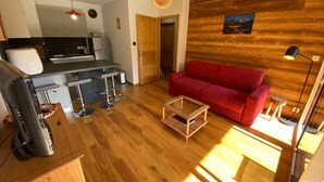 Un espace de vie compact comprenant une cuisine, un canapé rouge et un mur en bois.