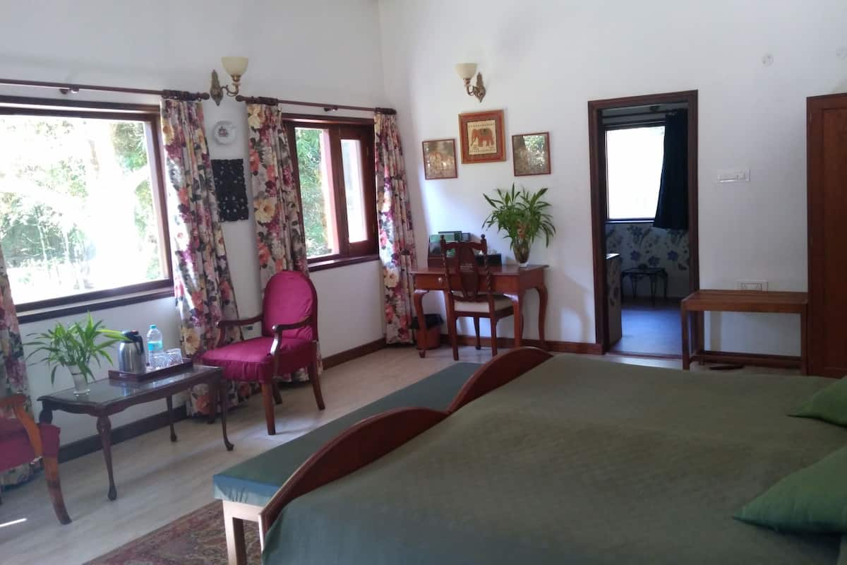 A room with a bed, a desk, a chair, and a wardrobe. There are windows with curtains, a lamp, and a plant.