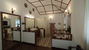 A bathroom with a large mirror, a sink, and a shower area. There are decorative wall sconces and a ceiling with a geometric pattern.