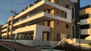 Un edificio residenziale a più piani con balconi, un'area parcheggio coperta e un giardino curato.