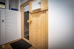 Una puerta de madera con un letrero encima, un armario blanco con listones horizontales y una alfombra oscura en el suelo.