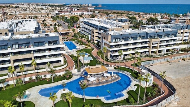Un resort con diversi edifici, una piscina centrale e una spiaggia.