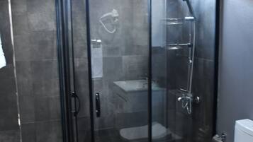 A modern bathroom with a glass-enclosed shower, a toilet, and a marble floor.