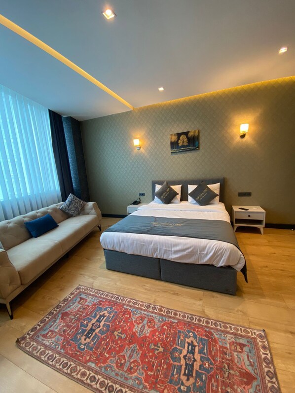 A modern bedroom with a large bed, a sofa, and a patterned rug.