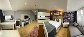 Una habitación de hotel moderna con cama, sofá, escritorio, televisor y un papel tapiz estampado.