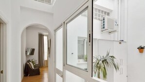 Et moderne interiør med trægulv, en stor glasdør der fører til en balkon, og en potteplante på væggen.