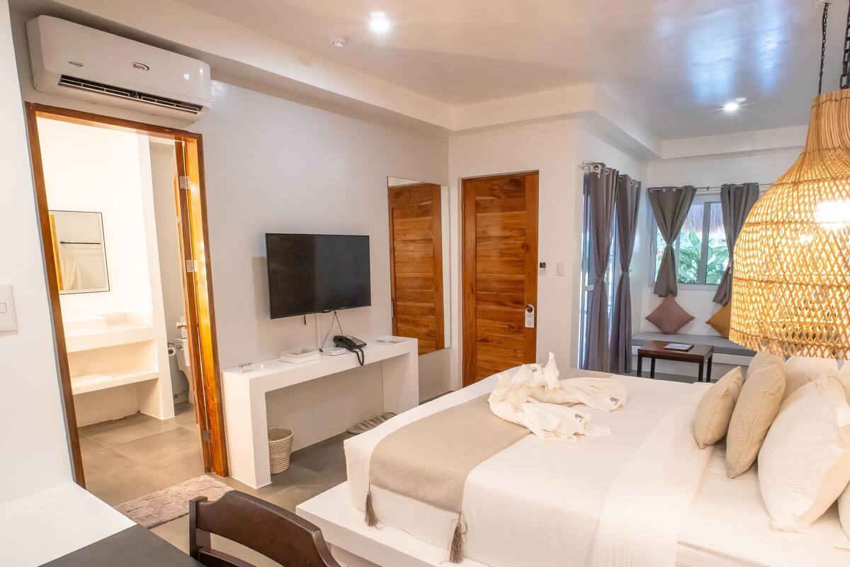 Una habitación de hotel con cama, mesita de noche, televisor y escritorio con silla.